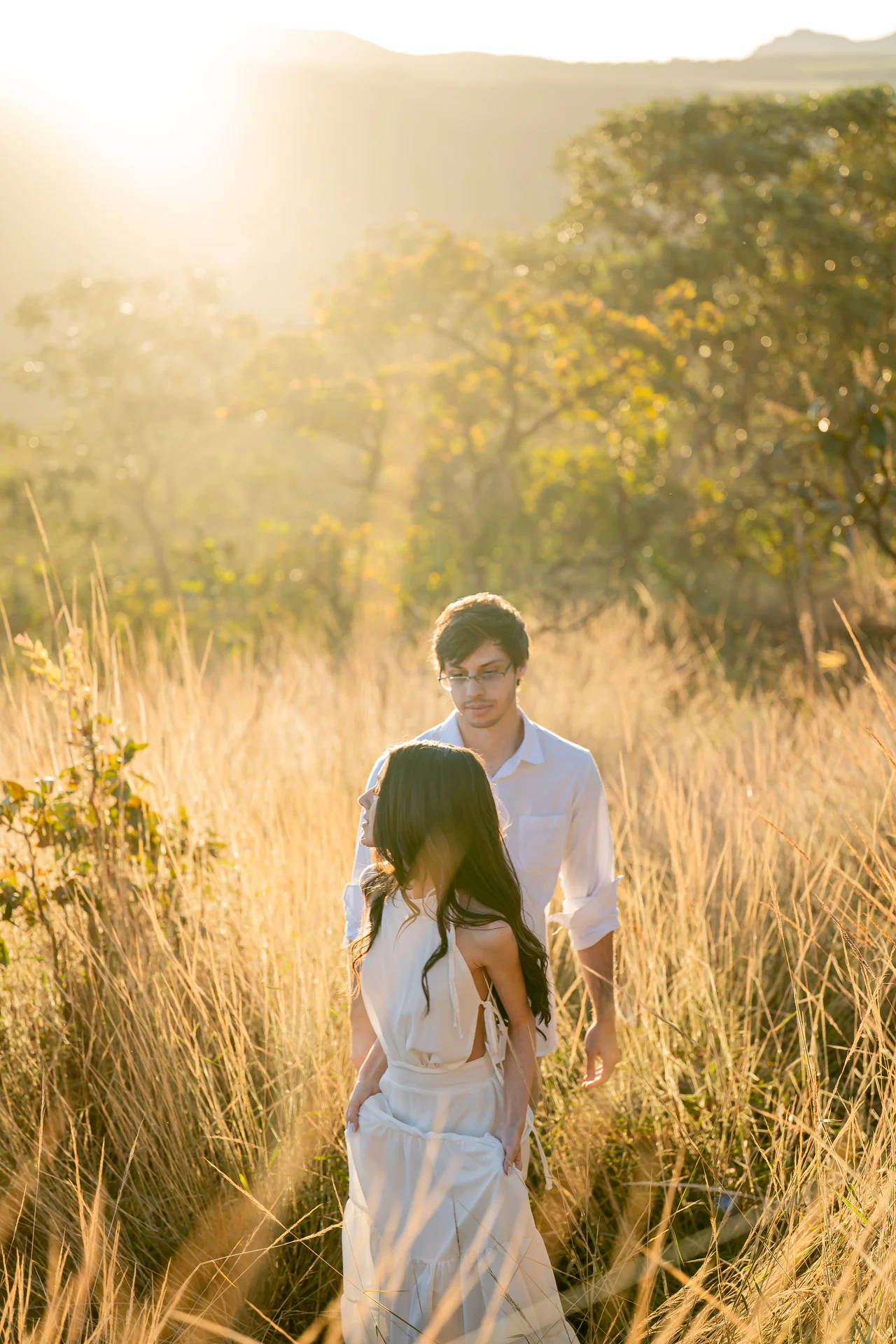 Anna Luiza e Vitor caminhando juntos pelo campo ao pôr do sol